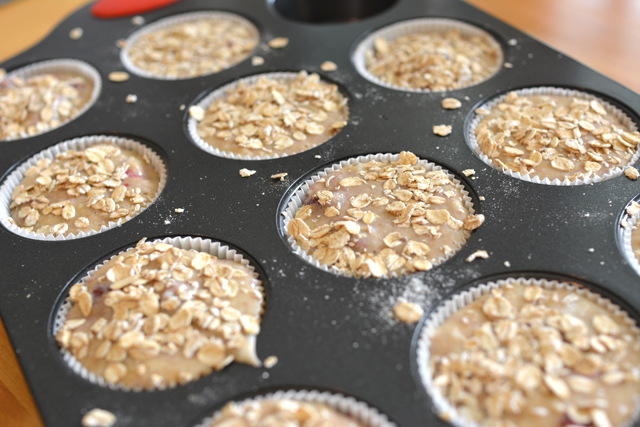 close up image of a muffin tray filled with batter topped with rolled oats