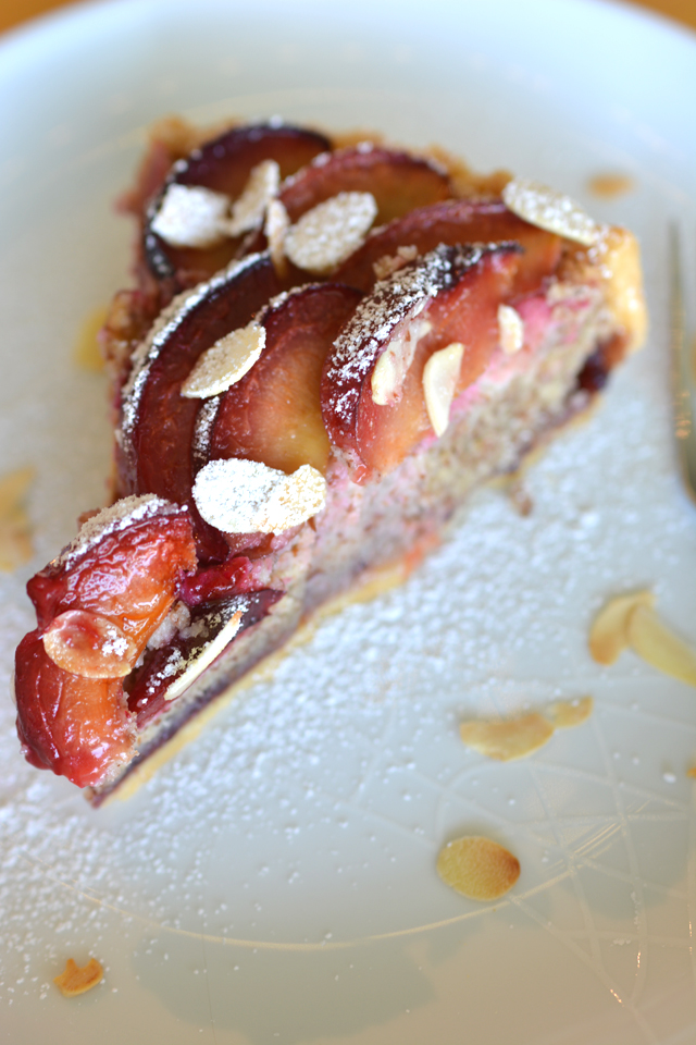close up image of a single slice of a freshly baked plum and almond tart