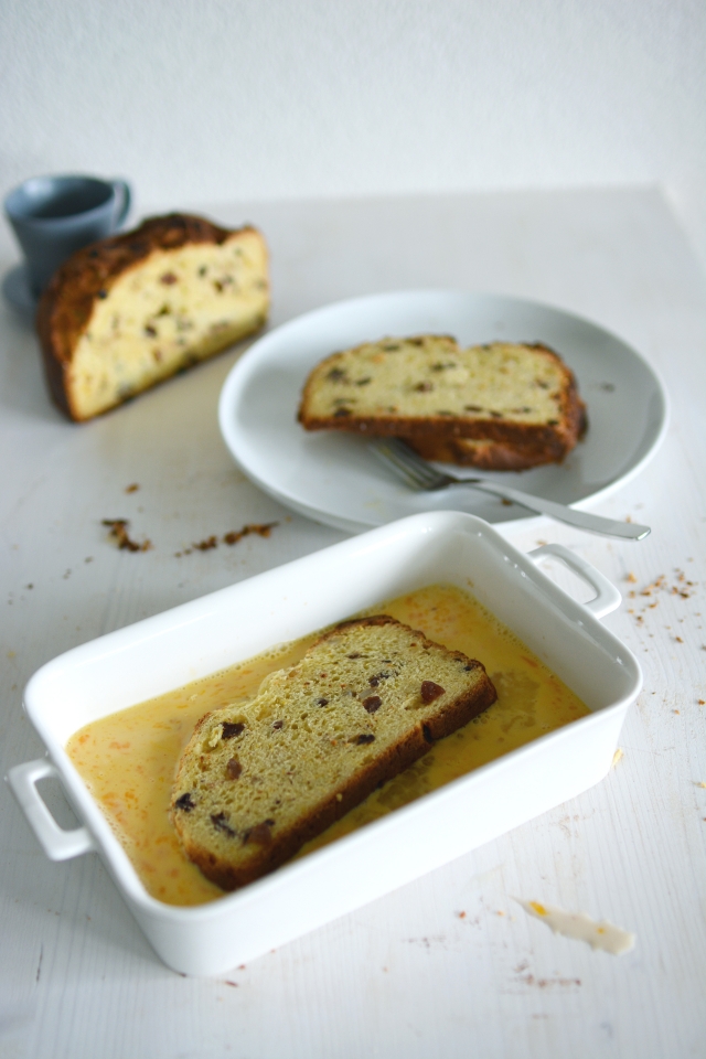image of a panettone slice being dipped into an egg mixture