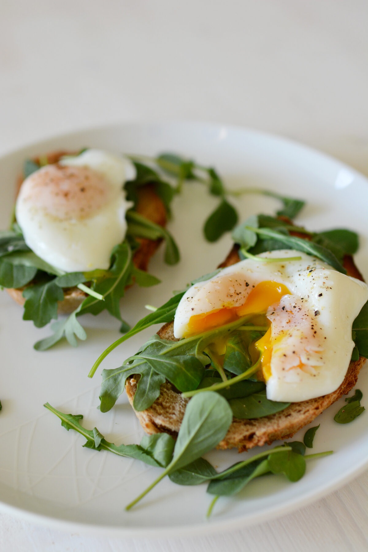 two toasted bread with poached eggs and herbs on top