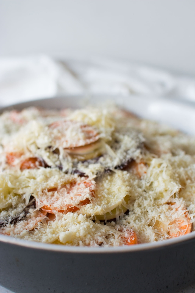 Layered slices of potatoes sprinkled with gruyere cheese on top.