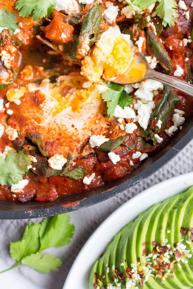 A spoon scopped a portion of Shakshuka with Spinach. 