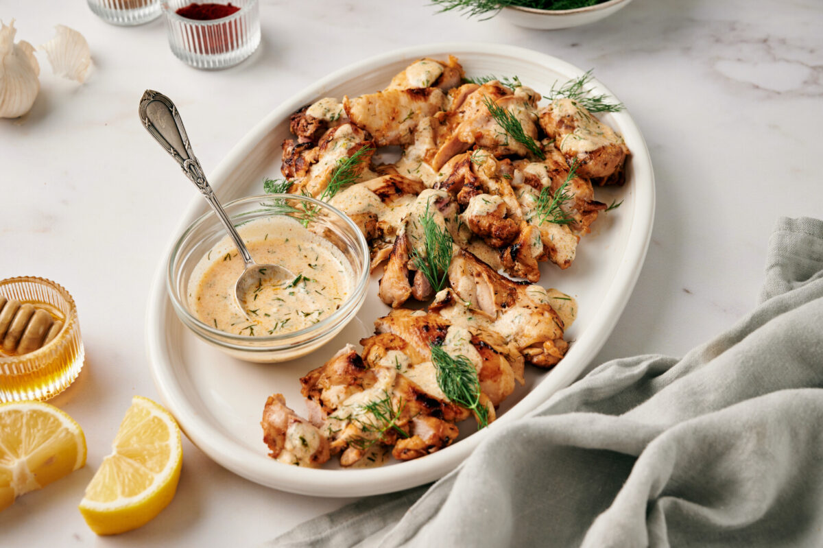 Lemon Dill Chicken on a white plate with sprigs of fresh dill and Dijon yogurt sauce.
